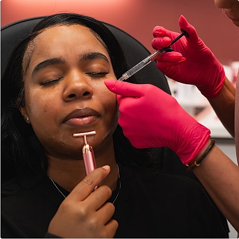 Medical professional holding a syringe with pink gloves.